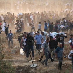 Personas transportan suministros de la Fundación Humanitaria de Gaza (FGH), un grupo de ayuda privado respaldado por Estados Unidos que ha eludido el sistema de la ONU en el territorio, mientras palestinos desplazados regresan de un centro de distribución de ayuda en el centro de la Franja de Gaza. La ONU y las principales organizaciones de ayuda se han negado a cooperar con la FGH, alegando la preocupación de que estuviera diseñada para atender objetivos militares israelíes. | Foto:Eyad Baba / AFP