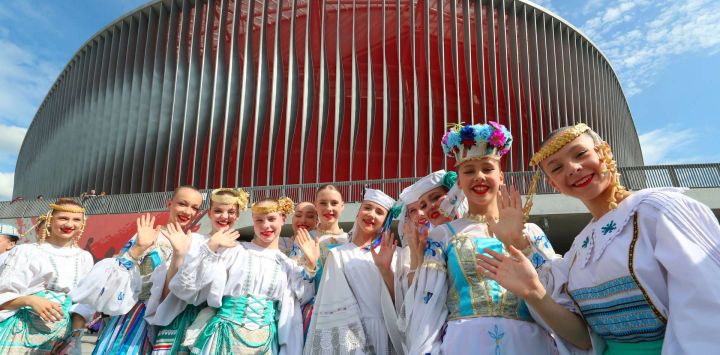 Imagen de mujeres vestidas con atuendos tradicionales posan para una fotografía grupal frente al Estadio Nacional de Fútbol de Bielorrusia, un proyecto histórico construido con apoyo chino, en Minsk, Bielorrusia.