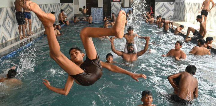 La gente se refresca zambulléndose en una piscina en un caluroso día de verano en Amritsar, India.