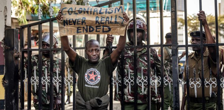 Un manifestante sostiene una pancarta mientras intenta bloquear la entrada a la sede del Servicio Nacional de Policía, exigiendo la dimisión de altos mandos tras la muerte de Albert Ojwang bajo custodia policial en Nairobi.