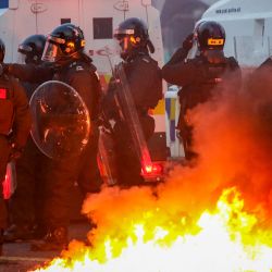 La policía se reúne para enfrentarse a los manifestantes junto a una hoguera prendida en las calles durante una manifestación antiinmigración en Ballymena, Irlanda del Norte. | Foto:PAUL FAITH / AFP