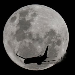 Un avión pasa frente a la luna llena, conocida como "Luna de Fresa", sobre la playa de Coogee en Sídney, Australia. | Foto:Saeed Khan / AFP