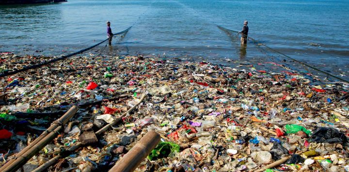 Imagen de pescadores trabajando con una red de pesca en una costa cubierta de basura plástica en la playa Sukaraja, en Bandar Lampung, en la provincia de Lampung, Indonesia.