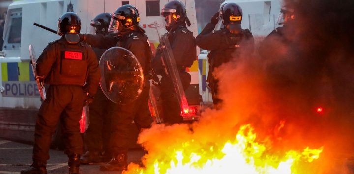 La policía se reúne para enfrentarse a los manifestantes junto a una hoguera prendida en las calles durante una manifestación antiinmigración en Ballymena, Irlanda del Norte.