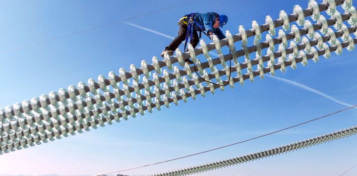 Vista aérea tomada con un dron de un trabajador operando sobre los cables del proyecto de transmisión de corriente continua de ultra alta tensión de ±800 kV Hami-Chongqing, en Hami, en la región autónoma uygur de Xinjiang, en el noroeste de China.