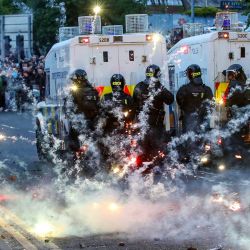 Fuegos artificiales lanzados contra la Policía Antidisturbios iluminaron la calle durante la tercera noche de manifestaciones antiinmigración en Ballymena, Irlanda del Norte. | Foto:PAUL FAITH / AFP