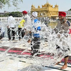 Voluntarios sijs lanzan cubos de agua para refrescar el suelo del Templo Dorado, en un caluroso día de verano en Amritsar, India. | Foto:Narinder Nanu / AFP