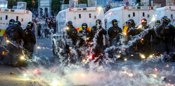 Fuegos artificiales lanzados contra la Policía Antidisturbios iluminaron la calle durante la tercera noche de manifestaciones antiinmigración en Ballymena, Irlanda del Norte.
