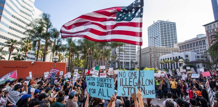 Manifestantes con pancartas y una bandera estadounidense se congregaron en Pershing Square para protestar contra las operaciones federales de inmigración en el centro de Los Ángeles.
