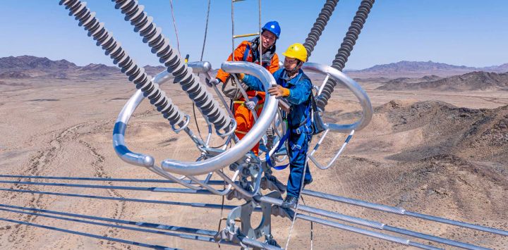 Vista aérea tomada con un dron de trabajadores revisando los cables del proyecto de transmisión de corriente continua de ultra alta tensión de ±800 kV Hami-Chongqing, en Hami, en la región autónoma uygur de Xinjiang, en el noroeste de China.