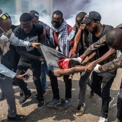 Manifestantes cargan a un hombre gravemente herido mientras intentan evacuarlo entre nubes de gas lacrimógeno disparadas por agentes de la Policía de Kenia, mientras estallan enfrentamientos durante una manifestación por la muerte del bloguero keniano Albert Ojwang, quien falleció bajo custodia policial, en el centro de Nairobi. | Foto:LUIS TATO / AFP