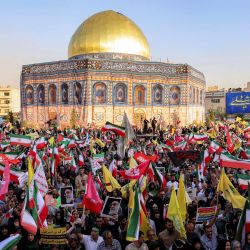 Manifestantes ondean banderas amarillas del Hezbolá libanés y de Irán frente a una réplica del Santuario de la Cúpula de la Roca de Jerusalén durante una manifestación en solidaridad con el gobierno contra los ataques de Israel a Irán y para conmemorar el Eid al-Ghadir, fecha en la que, según la creencia chiita, el profeta Mahoma designó a su sobrino y compañero Ali ibn Abi Talib como su sucesor. Esta manifestación se llevó a cabo en la plaza Enghelab de Teherán. | Foto:ATTA KENARE / AFP