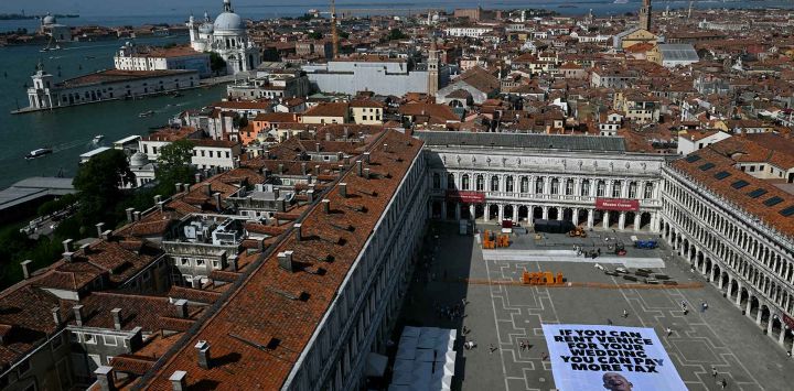 Ambientalistas de Greenpeace desplegaron una pancarta gigante con la imagen de Jeff Bezos y el mensaje "Si alquilas Venecia para tu boda, pagarás más impuestos". Foto de Stefano Rellandini / AFP