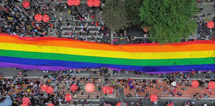 Esta vista aérea muestra a personas portando una enorme bandera arcoíris durante el 29º Desfile del Orgullo LGBT en Sao Paulo, Brasil. Foto de Miguel SCHINCARIOL / AFP