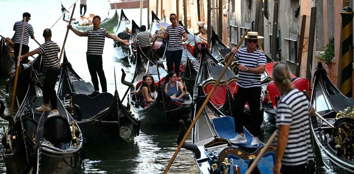 Gondoleros maniobran sus góndolas en un canal de la laguna de Venecia. Foto de Stefano Rellandini / AFP