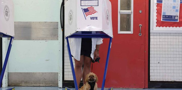 Una persona, junto a su perro, vota en un centro de votación en la escuela secundaria Louis D. Brandeis. Manhattan. Foto de TIMOTHY A. CLARY / AFP