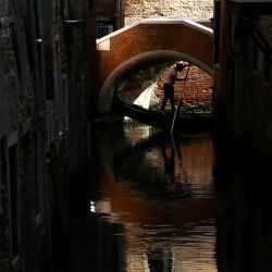 Un gondolero maniobra su góndola bajo un pequeño puente en la laguna de Venecia. Foto de Marco BERTORELLO / AFP | Foto:AFP