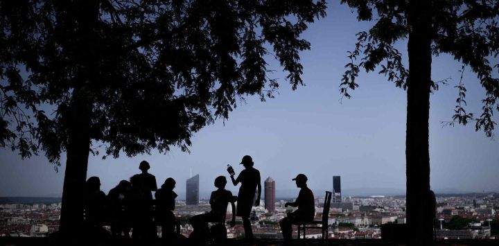 Residentes locales permanecen a la sombra de los árboles durante una ola de calor, en un parque sobre Lyon. Foto de JEFF PACHOUD / AFP
