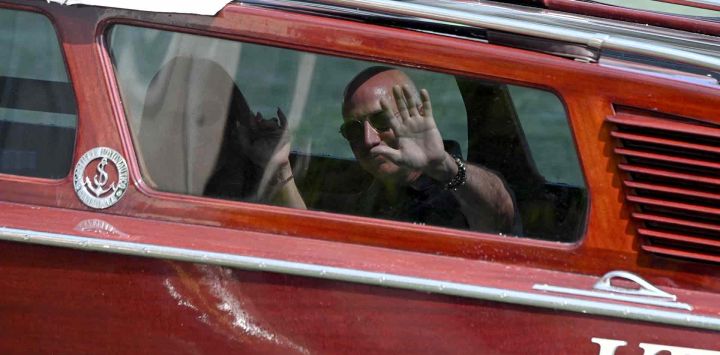El fundador de Amazon, Jeff Bezos, y Lauren Sanchez saludan desde el taxi acuático a su llegada al Hotel Aman. Foto de MARCO SABADIN / AFP