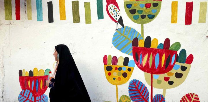  Una mujer iraní pasa junto a un mural en la plaza Enghlab de la capital, Teherán. Foto de ATTA KENARE / AFP