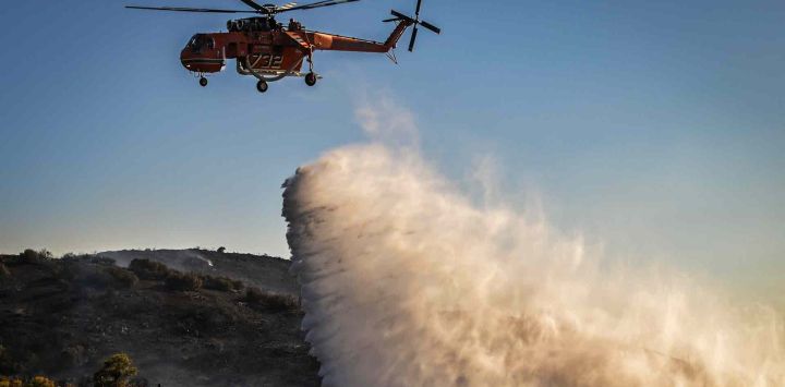 Un helicóptero de extinción de incendios Sikorsky S-64 Skycrane lanza agua sobre un incendio forestal cerca de Thymari. Foto de Aris MESSINIS / AFP