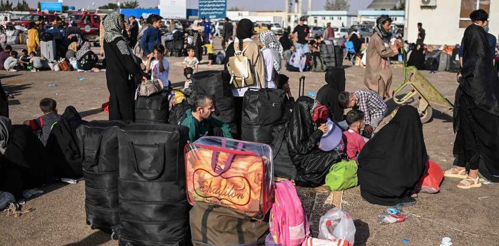 Refugiados afganos descansan junto a sus pertenencias tras llegar al cruce fronterizo de Islam Qala, entre Afganistán e Irán. Foto de Wakil Kohsar / AFP