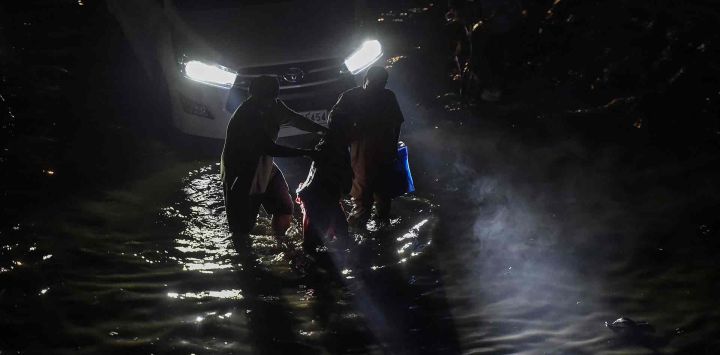 Los viajeros se abren paso por una calle inundada tras las fuertes lluvias en Jalandhar. Foto de Shammi MEHRA / AFP