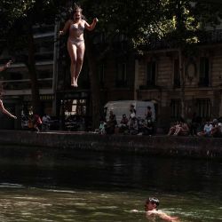 Jóvenes se lanzan al Canal Saint-Martin desde una pasarela en París. Foto de Thibaud MORITZ / AFP | Foto:AFP