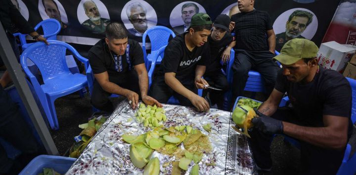 Voluntarios cortan fruta para distribuirla mientras iraquíes chiítas participan en una procesión por la calle Al-Kifah, en el centro de Bagdad. Foto de AHMAD AL-RUBAYE / AFP