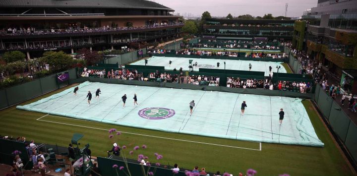 Los miembros del personal de campo retiran la cubierta protectora de la cancha en el Campeonato de Wimbledon 2025, en Londres. Foto de HENRY NICHOLLS / AFP