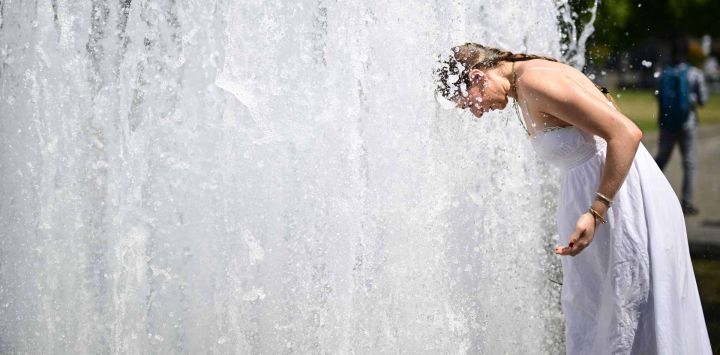 Una joven se sumerge en el agua fresca de una fuente del parque Lustgarten, en la Isla de los Museos de Berlín. Foto de Tobias SCHWARZ / AFP