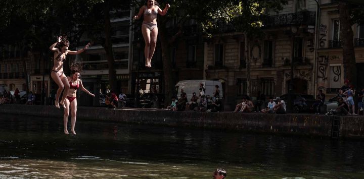 Jóvenes se lanzan al Canal Saint-Martin desde una pasarela en París. Foto de Thibaud MORITZ / AFP