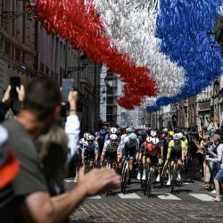 El pelotón circula bajo banderines decorativos colgados sobre el recorrido de la carrera en Aire-sur-la-Lys durante la tercera etapa de la 112ª edición del Tour de Francia, 178,3 km entre Valenciennes y Dunkerque (Dunkerque), en el norte de Francia. | Foto:afp
