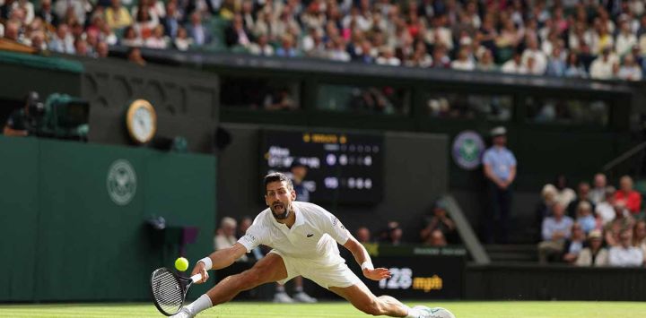 El serbio Novak Djokovic devuelve un golpe de derecha al australiano Alex De Minaur durante su partido de tenis de cuarta ronda individual masculino en el octavo día del Campeonato de Wimbledon 2025 en el All England Lawn Tennis and Croquet Club en Wimbledon, al suroeste de Londres.
