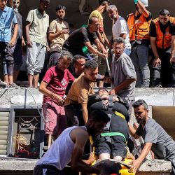Personas y personal de emergencia ayudan a evacuar a una mujer en camilla de un edificio que fue alcanzado por un bombardeo israelí en el campamento de Nuseirat para refugiados palestinos en el centro de la Franja de Gaza. | Foto:afp