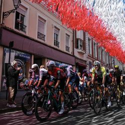 El pelotón circula bajo banderines decorativos colgados sobre el recorrido de la carrera en Aire-sur-la-Lys durante la tercera etapa de la 112ª edición del Tour de Francia, 178,3 km entre Valenciennes y Dunkerque (Dunkerque), en el norte de Francia. | Foto:afp
