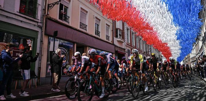 El pelotón circula bajo banderines decorativos colgados sobre el recorrido de la carrera en Aire-sur-la-Lys durante la tercera etapa de la 112ª edición del Tour de Francia, 178,3 km entre Valenciennes y Dunkerque (Dunkerque), en el norte de Francia.