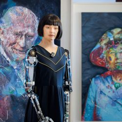Ai-Da, un robot humanoide ultrarrealista, observa las pinturas del rey Carlos III y la reina Isabel II de Gran Bretaña, expuestas en el marco de la Cumbre Mundial de IA para el Bien, organizada por la Unión Internacional de Telecomunicaciones (UIT) en Ginebra. | Foto:Valentin Flauraud / AFP