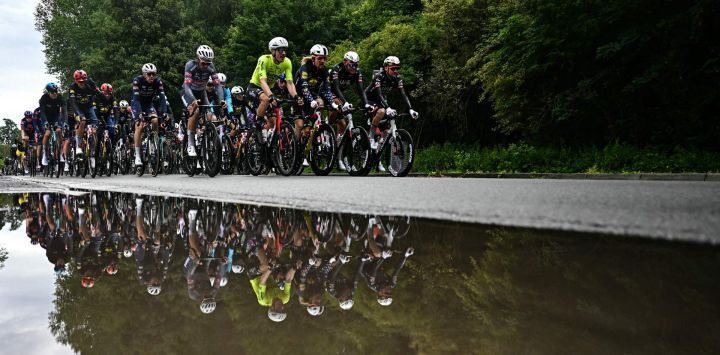 El pelotón se refleja en un charco mientras pedalean poco después del inicio de la tercera etapa de la 112.ª edición del Tour de Francia, una carrera ciclista de 178,3 km entre Valenciennes y Dunkerque (norte de Francia).
