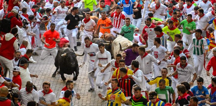 Participantes corren delante de los toros de Victoriano del Río durante el cuarto encierro de San Fermín en Pamplona, norte España.