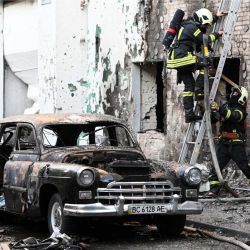 Bomberos junto a un coche incendiado tras los masivos ataques con drones y misiles rusos en la ciudad de Lviv, al oeste de Ucrania, durante la invasión rusa de Ucrania. | Foto:YURIY DYACHYSHYN / AFP