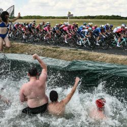 Los espectadores saltan a una piscina improvisada instalada a lo largo del recorrido de la carrera mientras el pelotón pasa en bicicleta, durante la novena etapa de la 112.ª edición del Tour de Francia, una carrera ciclista de 174,1 km entre Chinon y Chateauroux, en el centro de Francia. | Foto:MARCO BERTORELLO / AFP