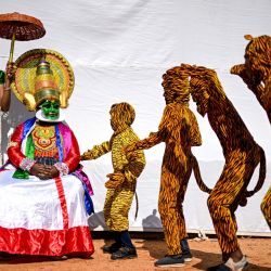 Una bailarina clásica de Kathakali, observa a los artistas ensayar la danza folclórica tradicional Pulikkali (Danza del Tigre) mientras esperan entre bastidores antes de su actuación en un festival cultural en Chennai, India. | Foto:R. Satish Babu / AFP