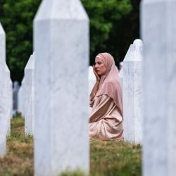 Una mujer reacciona sentada entre lápidas en el cementerio conmemorativo de la aldea de Potocari, cerca de Srebrenica, ciudad de Bosnia Oriental, en el 30.º aniversario de la masacre de Srebrenica. | Foto:ANDREJ ISAKOVIC / AFP