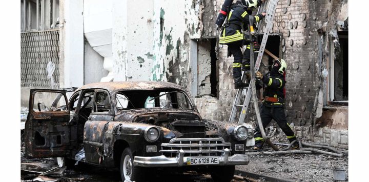 Bomberos junto a un coche incendiado tras los masivos ataques con drones y misiles rusos en la ciudad de Lviv, al oeste de Ucrania, durante la invasión rusa de Ucrania.