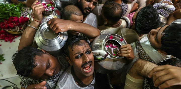 Devotos hindúes, portando vasijas llenas de agua bendita del río Ganges, entonan himnos mientras esperan para adorar al dios hindú Shiva en el templo de Kedareshwar en Varanasi, India.