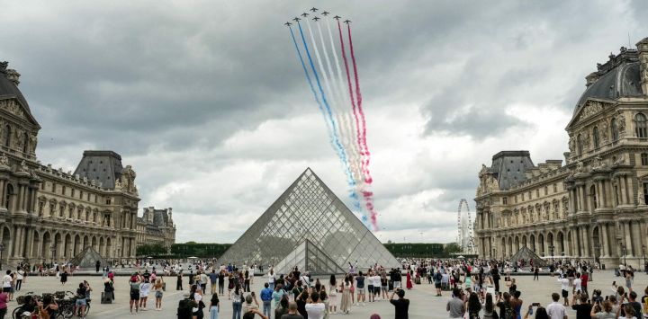 El equipo acrobático de élite de la Fuerza Aérea Francesa, "Patrouille de France" (PAF), lanza estelas con los colores nacionales de Francia durante un vuelo durante el desfile militar anual del Día de la Bastilla sobre la Pirámide del Louvre, diseñada por el arquitecto chino-estadounidense Ieoh Ming Pei, en París.