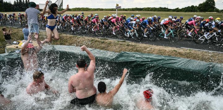 Los espectadores saltan a una piscina improvisada instalada a lo largo del recorrido de la carrera mientras el pelotón pasa en bicicleta, durante la novena etapa de la 112.ª edición del Tour de Francia, una carrera ciclista de 174,1 km entre Chinon y Chateauroux, en el centro de Francia.
