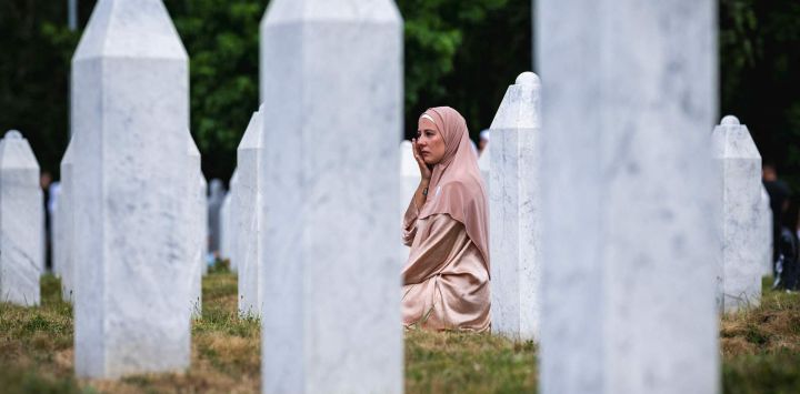 Una mujer reacciona sentada entre lápidas en el cementerio conmemorativo de la aldea de Potocari, cerca de Srebrenica, ciudad de Bosnia Oriental, en el 30.º aniversario de la masacre de Srebrenica.