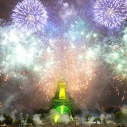 Los fuegos artificiales se encienden alrededor de la Torre Eiffel durante un espectáculo coreografiado de fuegos artificiales y drones para celebrar el Día de la Bastilla, en París. | Foto:DIMITAR DILKOFF / AFP
